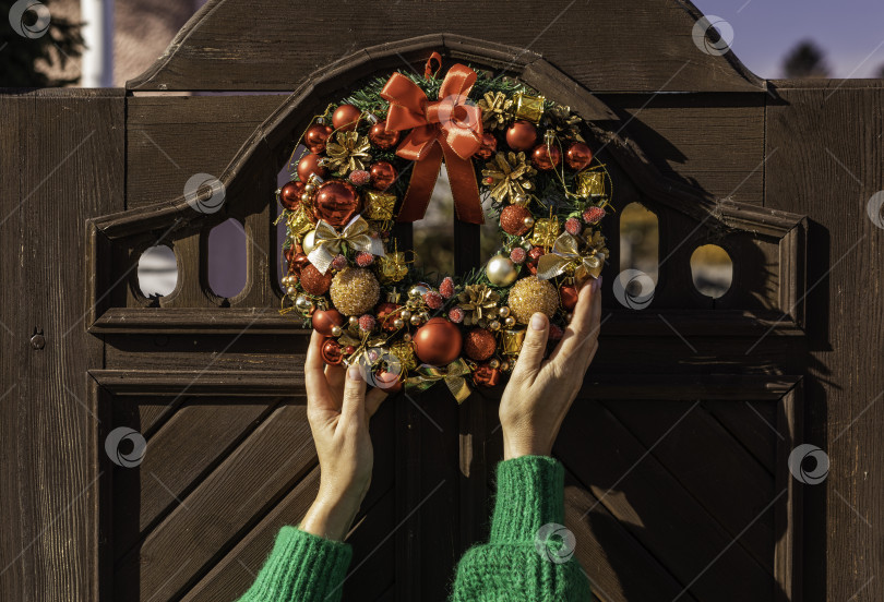 Скачать женщина, вешающая еловый венок на рождество. Рождественский сочельник и украшение. новый год фотосток Ozero