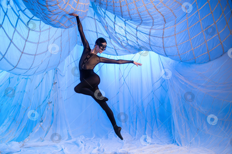 Скачать Женщина танцует в комнате с белыми портьерами из тонкой воздушной ткани, освещенной голубыми прожекторами. фотосток Ozero