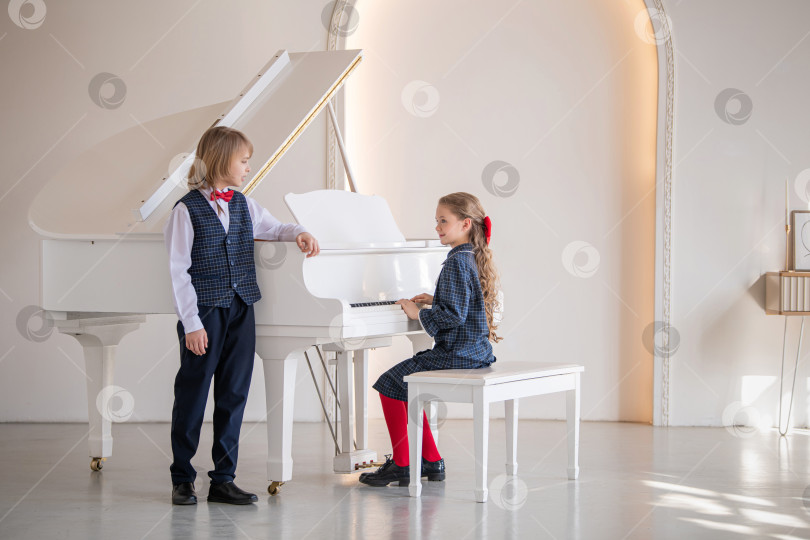 Скачать Двое детей играют на пианино и поют в белой комнате. фотосток Ozero