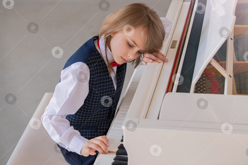 Скачать Маленький мальчик играет на большом белом пианино в светлой солнечной комнате фотосток Ozero