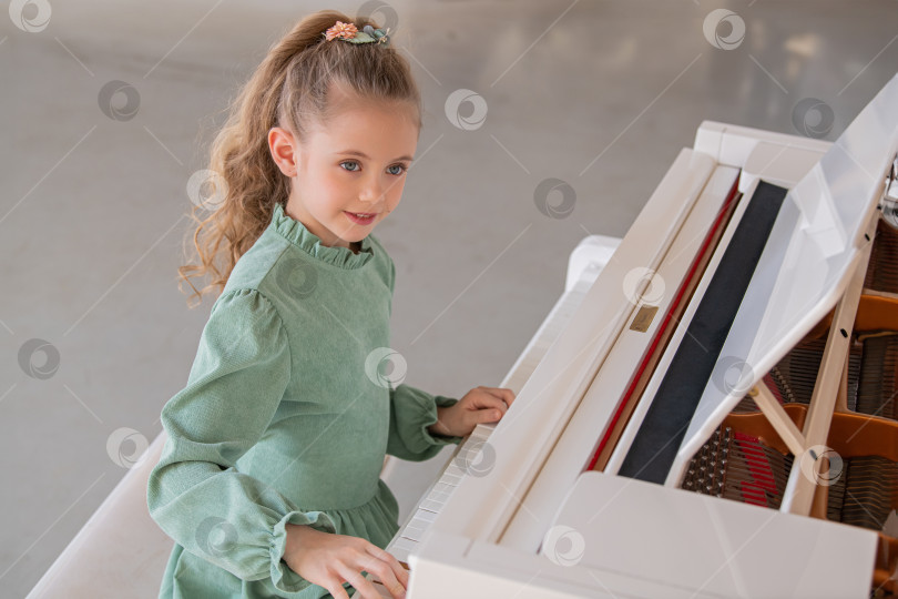 Скачать Молодая девушка в зеленом платье играет на пианино фотосток Ozero