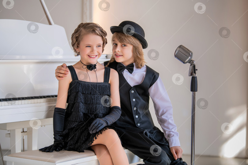 Скачать Двое детей, одетых в черно-белое, сидят перед пианино. фотосток Ozero