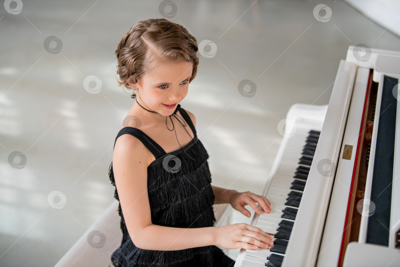 Скачать Молодая девушка в черном платье играет на пианино. фотосток Ozero