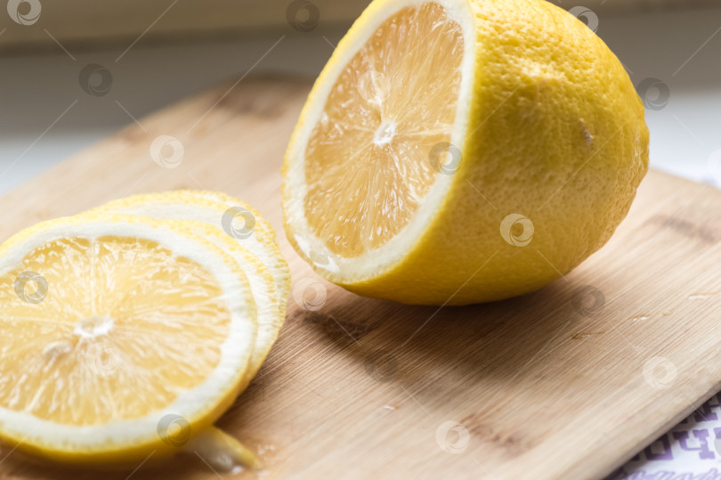 Скачать Половинка лимона, нарезанная кусочками, лежит на разделочной доске. Крупный план фотосток Ozero