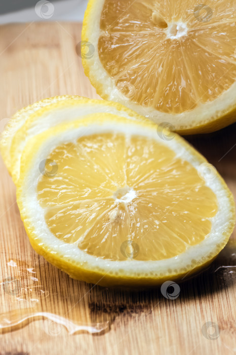 Скачать Выложите ломтики лимона на деревянную разделочную доску. Спелый сочный лимон, истекающий соком. фотосток Ozero