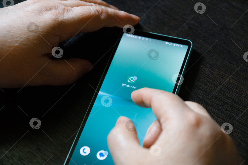 Скачать Пенсионерка держит в своих руках телефон с иконкой приложения Whats App. Москва, Россия, 9 июня 2024 года. фотосток Ozero