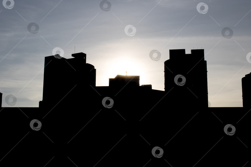 Скачать Силуэт городского горизонта с солнцем, пробивающимся сквозь облака фотосток Ozero