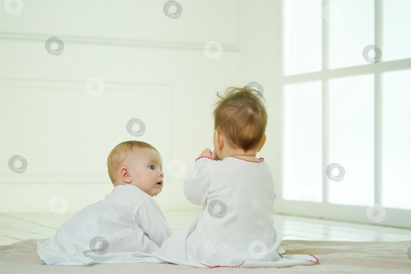 Скачать Двое маленьких новорожденных детей находятся в светлой комнате. Понятие детства фотосток Ozero