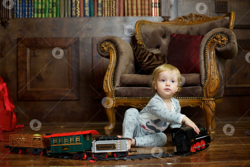Скачать Маленький мальчик сидит на полу и играет с заводным поездом. фотосток Ozero