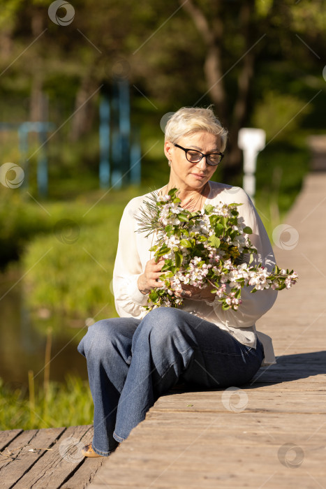 Скачать Красивая зрелая белая женщина с короткими волосами и в очках, с букетом яблоневых цветов фотосток Ozero