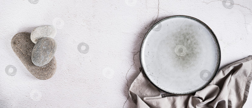Скачать Пустая керамическая тарелка, камни и салфетка на сером фоне вид сверху на веб-баннер фотосток Ozero