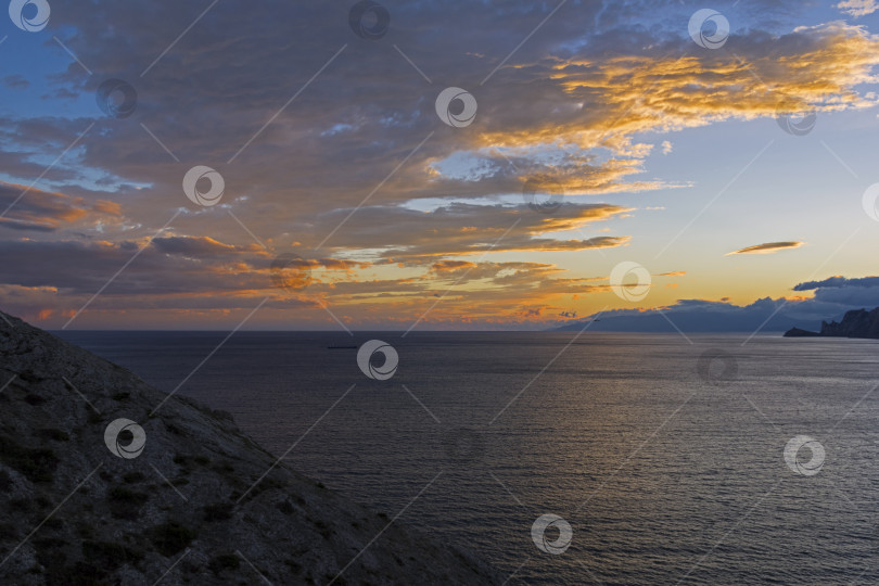 Скачать Облака над морем, освещенные заходящим солнцем. фотосток Ozero