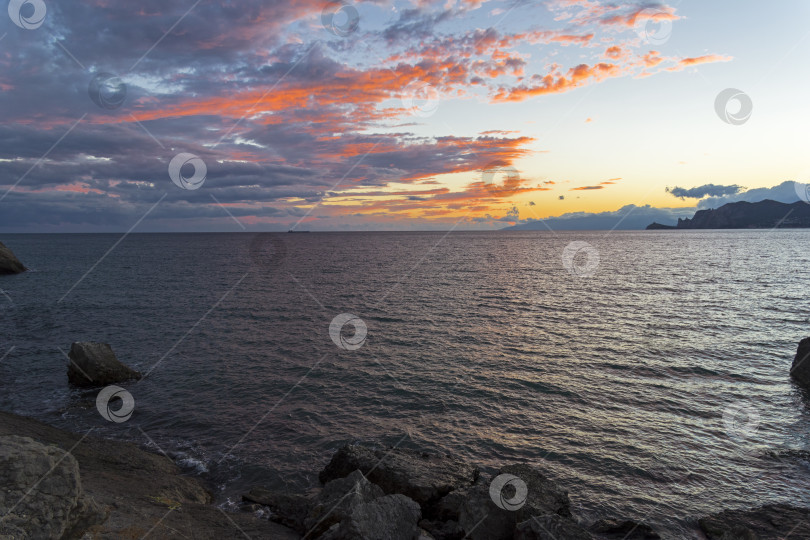 Скачать Облака над морем, освещенные заходящим солнцем. фотосток Ozero