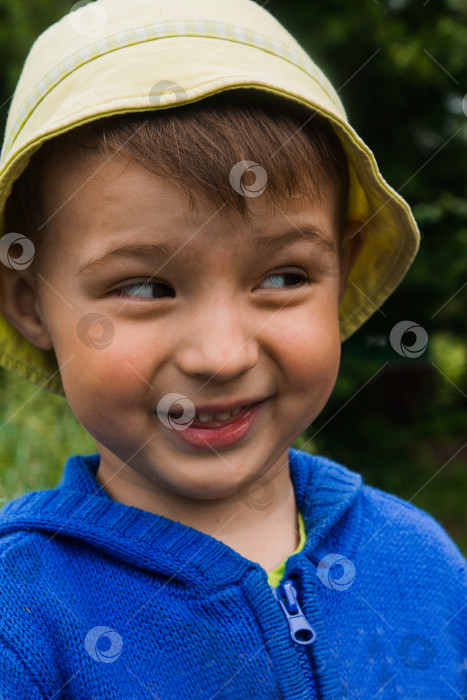 Скачать Маленький мальчик в яркой шляпе и синем свитере косит глаза и улыбается фотосток Ozero