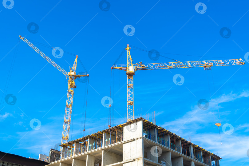 Скачать Два крана работают на строительстве здания под ясным голубым небом фотосток Ozero