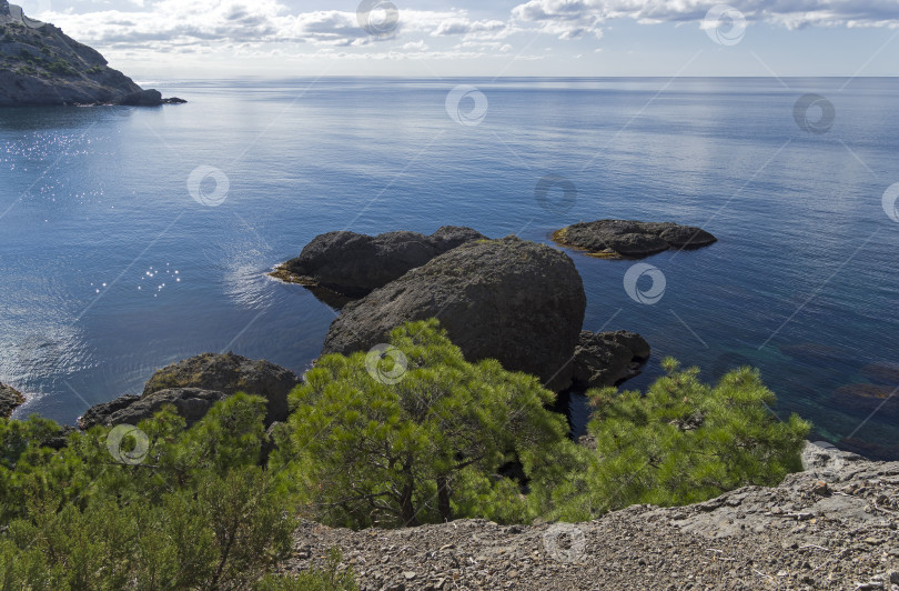 Скачать Каменистый берег моря тихим солнечным утром. фотосток Ozero