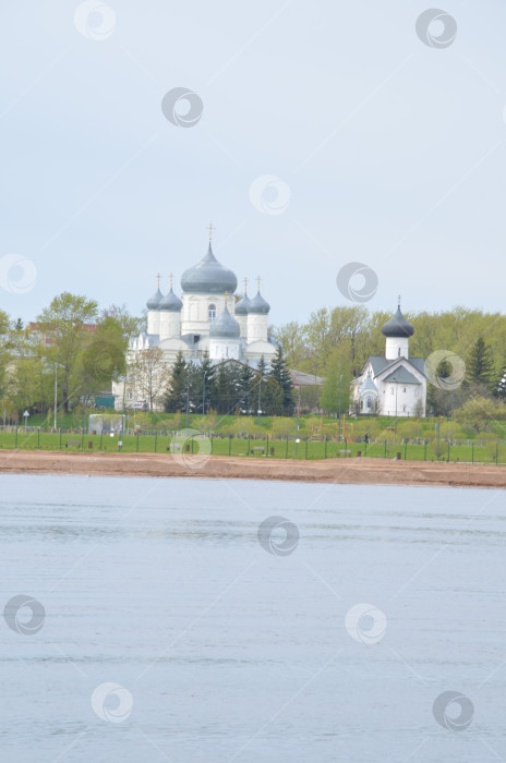 Скачать Великий Новгород, Россия - 13.05.2024: Вид на Зверин-Покровский дворец в Великом Новгороде со сторо-ны рек Волхов: Покровский собор (рубеж XIX-XX вековъ) и Симеоновская церковь (Церковь Симеона Богоприимца XV века) фотосток Ozero