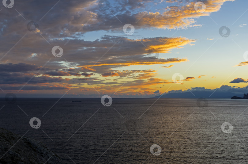 Скачать Облака над морем, освещенные заходящим солнцем. фотосток Ozero