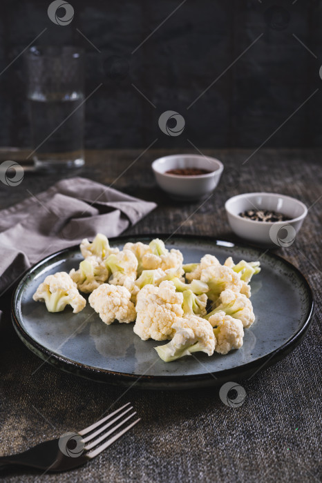 Скачать Кусочки сырой цветной капусты для диетического питания на тарелке на столе в вертикальном положении фотосток Ozero