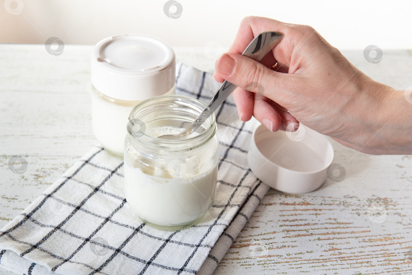Скачать Женская рука пробует ложкой свежеприготовленный йогурт. фотосток Ozero