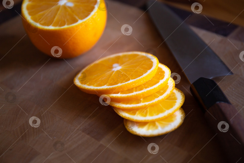 Скачать Нож шеф-повара и ломтики апельсина лежат на разделочной доске фотосток Ozero