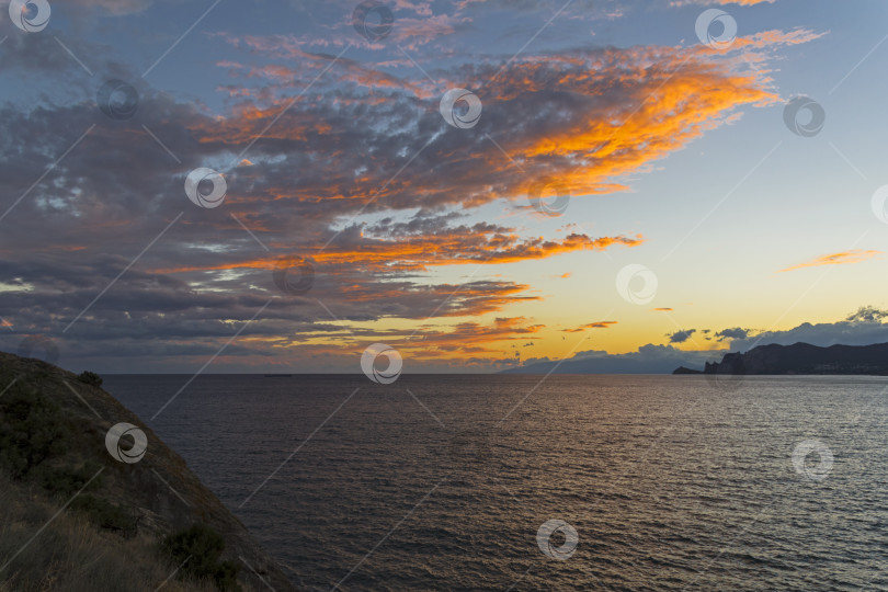 Скачать Облака над морем, освещенные заходящим солнцем. фотосток Ozero