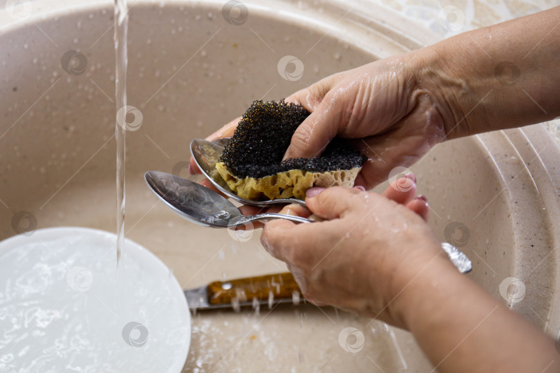 Скачать Женские руки моют посуду ложками в кухонной раковине. Концепция домашнего хозяйства фотосток Ozero