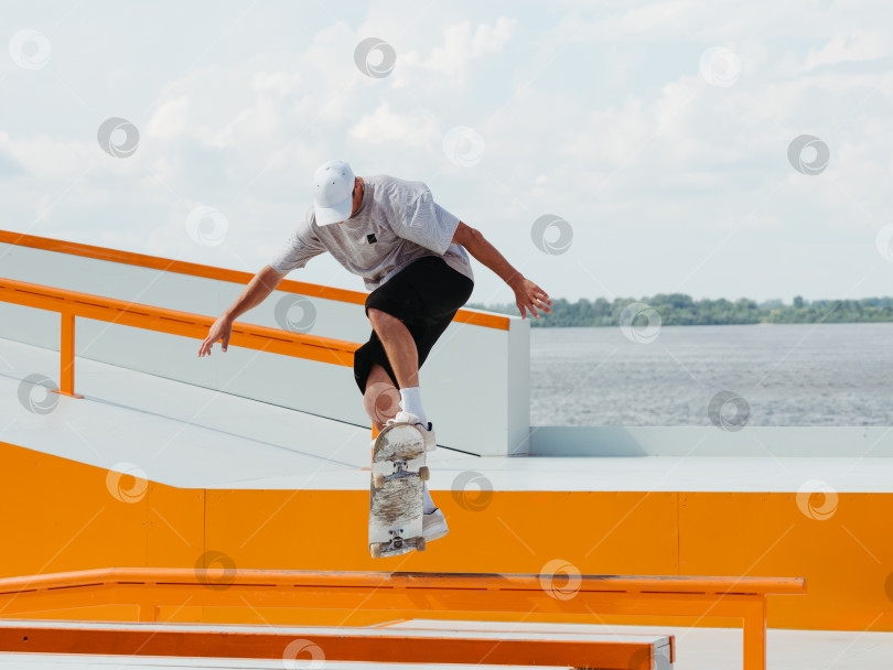Скачать Молодой человек делает прыжковый трюк на скейтборде фотосток Ozero