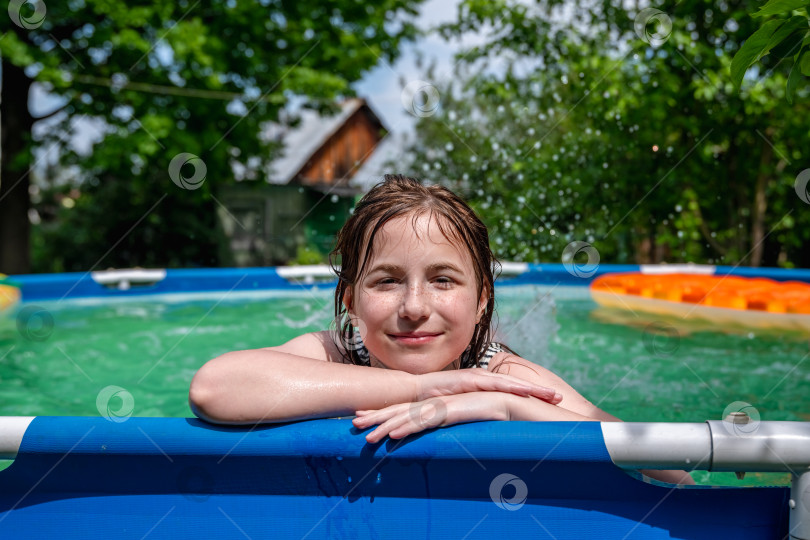 Скачать Девочка-подросток плавает в каркасном бассейне за городом, улыбаясь фотосток Ozero