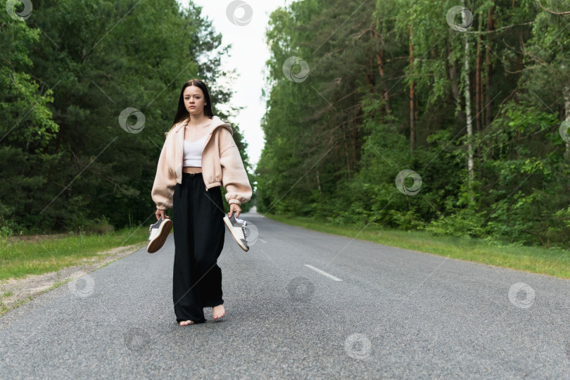 Скачать Молодая девушка идет босиком по дороге фотосток Ozero