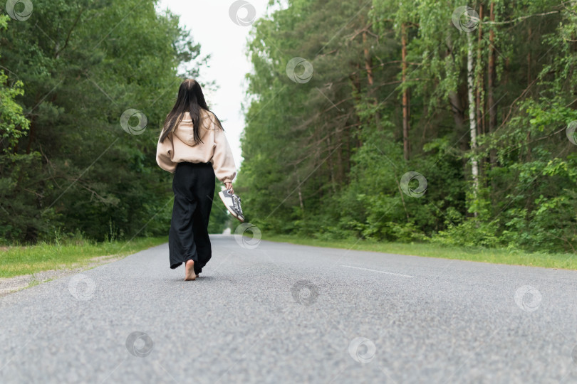 Скачать Молодая девушка идет босиком по дороге фотосток Ozero