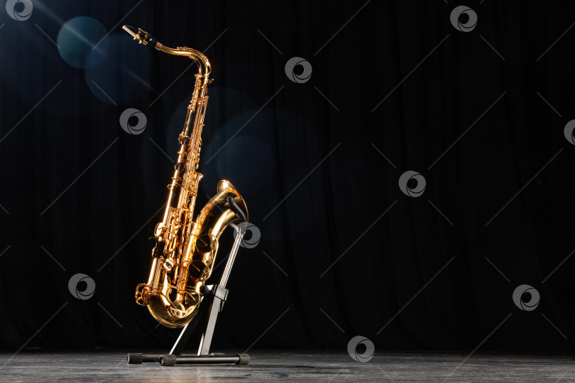 Скачать Золотой саксофон на черном полу концертной сцены. фотосток Ozero