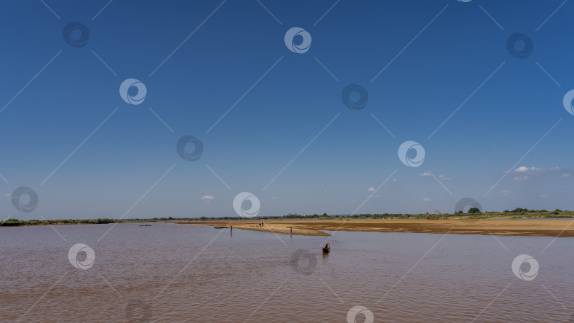 Скачать Спокойная красно-коричневая река. Каноэ плывет по руслу реки. фотосток Ozero