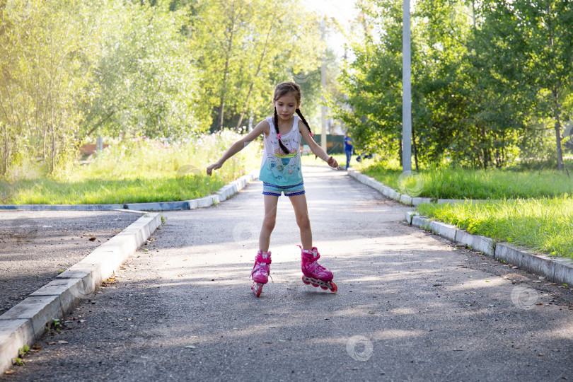 Скачать Маленькая девочка в парке катается на роликах фотосток Ozero