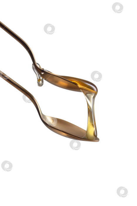 Скачать Золотые ложки с золотистым жидким медом на белом фоне фотосток Ozero