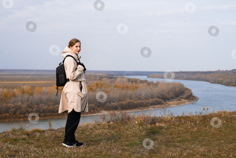 Скачать Молодая девушка стоит на высоком берегу и смотрит на прекрасную природу фотосток Ozero