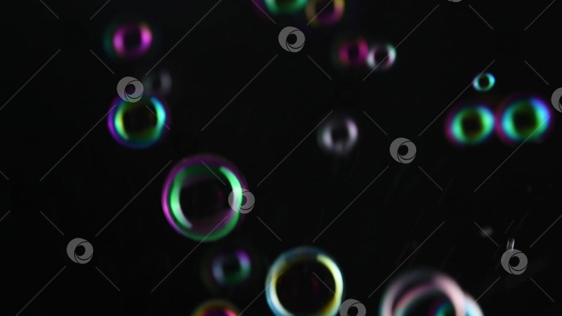 Скачать Фон из мыльных пузырей. Разноцветные мыльные пузыри летают по черному фону. фотосток Ozero