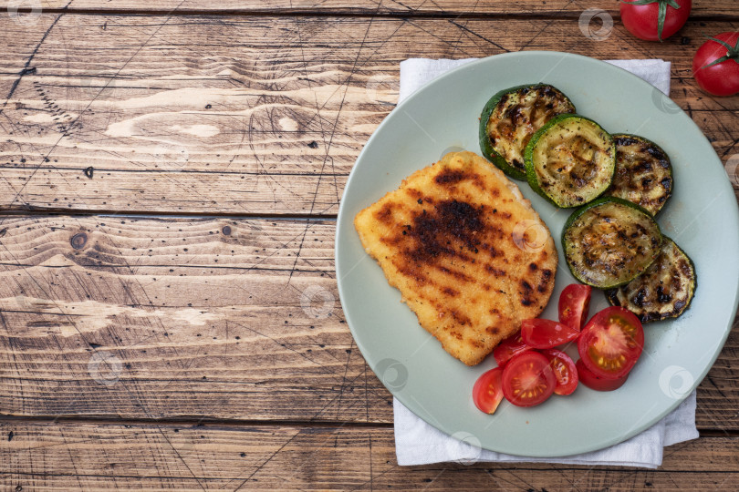 Скачать Шницель из курицы и цуккини, приготовленный на гриле. Свежие помидоры на тарелке. Готов вкусный ужин-ланч. Деревянный фон копирует пространство. фотосток Ozero