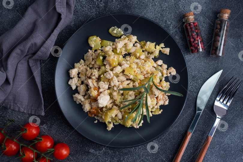 Скачать Тушеный куриный фарш с овощами, цуккини, перцем и специями на черной тарелке. фотосток Ozero