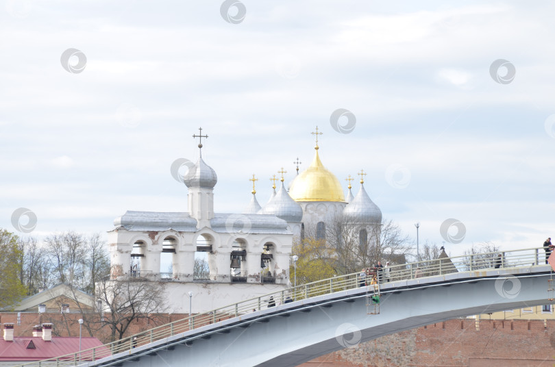 Скачать Великий Новгород, Россия - 13.05.2024: Вид на Кремль Великого Новгорода: Государственный собор (правительственный храм XI века), именуемый Государственным собором , крепкие стены, Горбатый мост фотосток Ozero