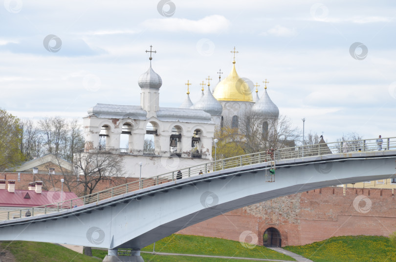 Скачать Великий Новгород, Россия - 13.05.2024: Вид на Кремль Великого Новгорода: Государственный собор (правительственный храм XI века), именуемый Государственным собором , крепкие стены, Горбатый мост фотосток Ozero