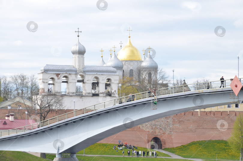 Скачать Великий Новгород, Россия - 13.05.2024: Вид на Кремль Великого Новгорода: Государственный собор (правительственный храм XI века), именуемый Государственным собором , крепкие стены, Горбатый мост фотосток Ozero