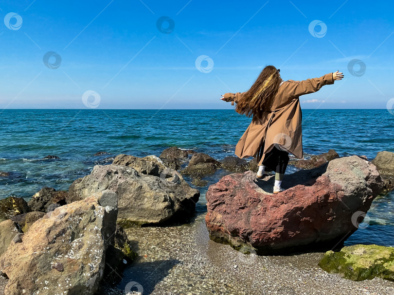 Скачать Женщина с длинными волосами стоит на берегу моря одетая фотосток Ozero