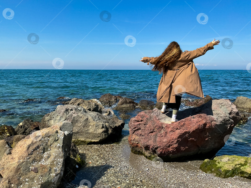 Скачать Женщина с длинными волосами стоит на берегу моря одетая фотосток Ozero