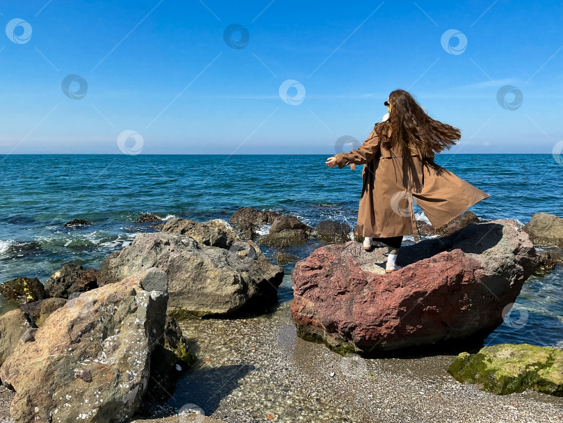 Скачать девушка с длинными волосами стоит на берегу моря одетая фотосток Ozero