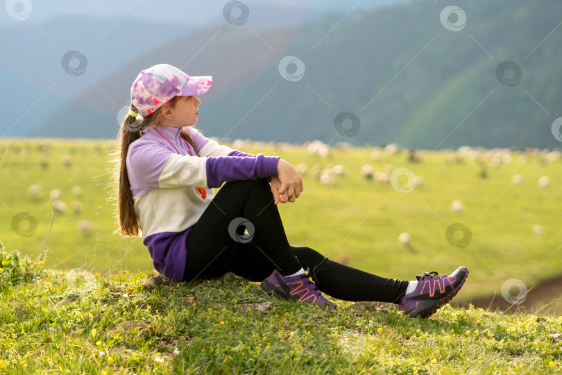 Скачать Девушка сидит на травянистом холме и смотрит вдаль. фотосток Ozero