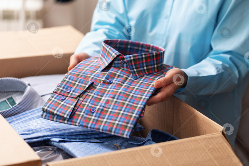 Скачать Женщина складывает сложенные новые рубашки в коробку для отправки на рынок, концепция на тему малого бизнеса фотосток Ozero