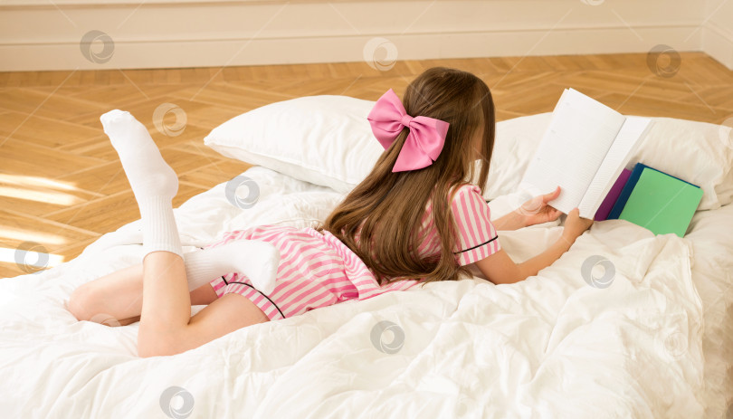 Скачать Девушка в розовой пижаме читает книгу фотосток Ozero