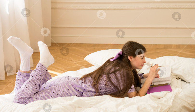 Скачать Девочка-подросток читает книгу на кровати фотосток Ozero