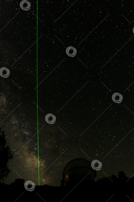 Скачать Зеленый лазерный луч, уходящий ночью в звездное небо. фотосток Ozero